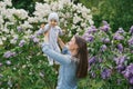 Happy European mother lifts up her little smiling son in her arms in the spring on a walk in the park Royalty Free Stock Photo