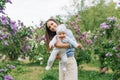 Happy European mother lifts up her little smiling son in her arms in the spring on a walk in the park Royalty Free Stock Photo