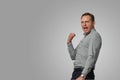 Happy excite young man in grey pullover screaming and celebrating his succcess over white background. Emotional, brave