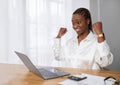 Happy excited african lady entrepreneur sitting at workplace, celebrating success Royalty Free Stock Photo