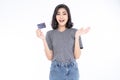 Happy excited amazed young Asian woman in grey t-shirt and jeans holding bank card holding credit card on isolated over white Royalty Free Stock Photo