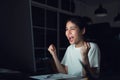 Happy excited Asian business woman celebrating success and working on computer at night. Royalty Free Stock Photo