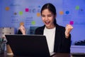 Happy excited Asian business woman celebrating success and working on laptop on the table at night. Royalty Free Stock Photo