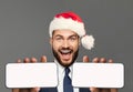 Happy excited businessman in Santa hat showing two smart phones. Smartphone with blank empty white screen display for new Royalty Free Stock Photo