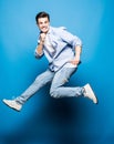 Happy excited cheerful young man jumping and celebrating success isolated on blue background Royalty Free Stock Photo