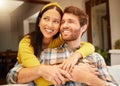 Happy and excited couple hugging thinking of future relaxing and sitting on a couch at home. Relaxed diverse interracial