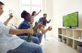 Happy excited diverse friends screaming while watching football match on TV at home Royalty Free Stock Photo