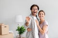 Happy excited european young lady hug guy in glasses with open mouth and hold keys in room with cardboard boxes