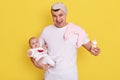 Happy excited father with newborn baby in hands, feeding kid with milk, handsome guy with blindfold over forehead yelling Royalty Free Stock Photo