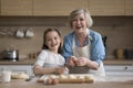 Happy excited grandma and joyful grandkid girl baking at kitchen