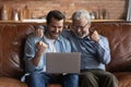 Happy excited grown son and mature 70s father using laptop Royalty Free Stock Photo