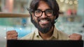 Happy excited Indian worker man in glasses celebrate business success online winning good result with laptop looking at Royalty Free Stock Photo