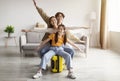 Happy excited korean young girl, mom and dad spread arms to sides like airplane, sit on yellow suitcase