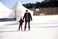 Happy excited little boy and his young father learning ice-skating