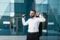 Happy excited mature businessman celebrate victory with fists raised in the air staying against modern glass office Royalty Free Stock Photo