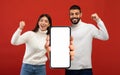 Happy excited millennial arab couple celebrate victory with hands gesture, show big smartphone with blank screen Royalty Free Stock Photo