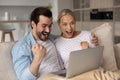 Happy excited millennial couple with digital device celebrating success