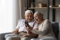 Happy excited older married couple using smartphone