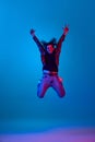 Happy, excited, positive young man with curly hair, unshaved face, wearing casual clothes and jumping against blue Royalty Free Stock Photo