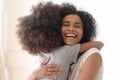 Happy excited single african american mother cuddling little preschool daughter.