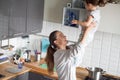 Happy smiling mum holding daughter in kitchen