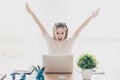 Happy excited successful businesswoman triumphing with laptop sitting at workstation workplace sitting at table in light room rais Royalty Free Stock Photo