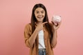 Happy excited teen girl pointing at piggy bank and looking at camera Royalty Free Stock Photo