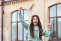 Happy excited teenage girl shouting making winner gesture in casual style blurry outdoors