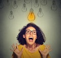 Happy excited woman in glasses looking up at bright light idea bulb above head Royalty Free Stock Photo
