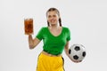 Happy excited woman in green yellow football kit holding beer mug and football ball supports favorite team. Soccer fans Royalty Free Stock Photo