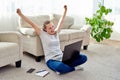 Happy excited woman at home triumphing with raised hands. Girl completed task and celebrating her success. I`m winner! Yes! Did