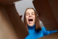 Happy and excited young adult woman looking inside carton box. Looking cheerful and overjoyed, screaming with happiness, good Royalty Free Stock Photo