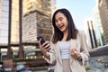 Happy excited young Asian business woman winner holding mobile phone in city. Royalty Free Stock Photo