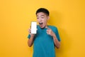 Happy Excited Young Asian man shock pointing blank phone screen for copy space and showing white phone screen at camera Royalty Free Stock Photo