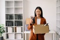 Happy and excited young beautiful Asian woman office worker celebrating her resignation, carrying her personal stuff. leaving job Royalty Free Stock Photo