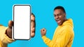 Happy excited young black guy show first, celebrate win, success, near hand with phone with empty screen