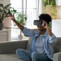 Happy excited young black woman enjoying virtual reality shopping experience while resting at home Royalty Free Stock Photo