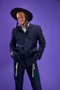 Happy and excited young Jewish man with sidelocks in hat, costume posing against purple studio background
