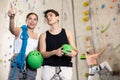 Happy excited young male and female visitors discussing upcoming climbing artificial training rock wall in indoor Royalty Free Stock Photo