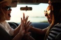 Happy excited young women driving in car and making high five gesture on summer vacation trip. Two girls rejoice they Royalty Free Stock Photo