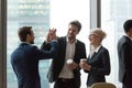 Happy executives give high five during friendly talk in office