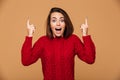 Happy exited young woman in red sweater pointing up with two fin Royalty Free Stock Photo