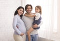 Smiling Man, Pregnant Woman And Their Little Daughter Posing At Home Royalty Free Stock Photo