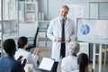 Happy experienced clinician in lab coat standing in front of audience