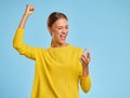 Happy expressive woman  with smartphone shouts celebrating victory success and triumph on  blue background Royalty Free Stock Photo