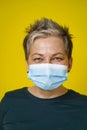 Happy eyes smiling grey short haired doctor woman wearing medical face mask looking at camera wearing green blouse Royalty Free Stock Photo