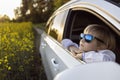 happy face of a little boy in blue sunglasses looks out the open car window and looks around with interest Royalty Free Stock Photo
