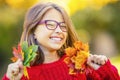 Happy fall girl smiling and joyful holding autumn leaves. Beautiful young girl with maple leaves in red cardigan