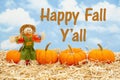 Happy Fall Y`all message with scarecrow and orange pumpkins on straw hay