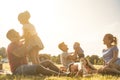 Happy families doing picnic in nature park outdoor - Young parents having fun with children in summer time laughing together -